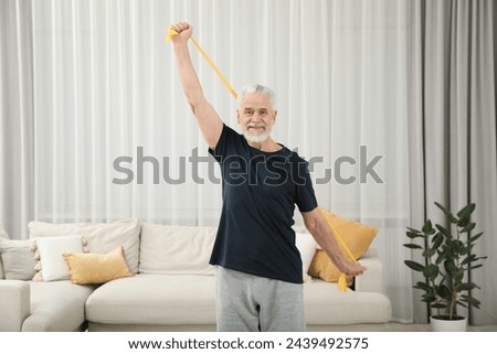Senior man doing exercise with fitness elastic band at home