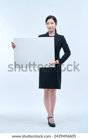  A beautiful Asian woman in a business suit is holding a white board and making various expressions and gestures