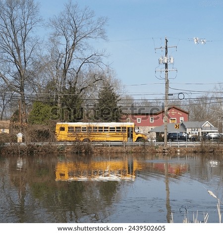 The yellow school bus drives by the lake. Royalty-Free Stock Photo #2439502605