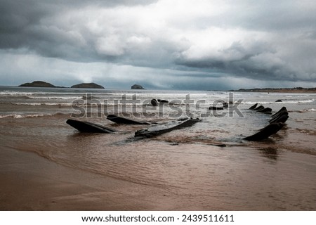 A low tide  of waters of the North Sea shows a wreck of a fishing boat on the bottom before a storm. Picture taken in Scotland,  on a beach Yellowcraig beach,  between Edinburgh and North Berwick. 