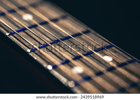 Part of an acoustic guitar, guitar fretboard on a black background. Royalty-Free Stock Photo #2439518969