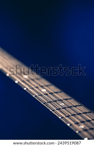 Part of an acoustic guitar, guitar fretboard on a black background. Royalty-Free Stock Photo #2439519087