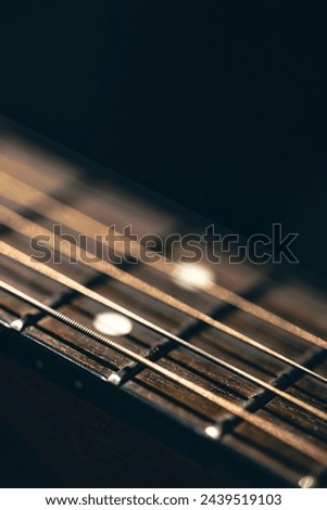 Part of an acoustic guitar, guitar fretboard on a black background. Royalty-Free Stock Photo #2439519103