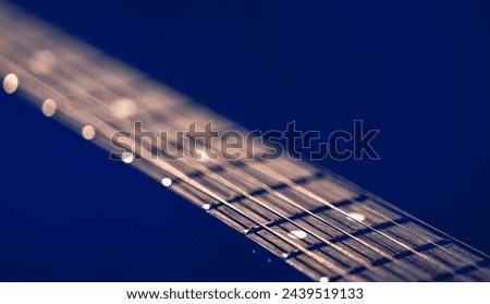 Part of an acoustic guitar, guitar fretboard on a black background. Royalty-Free Stock Photo #2439519133