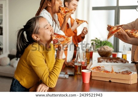 multiracial group of young people at a house party ordered pizza and beer, students of different ethnicities at a house party drink alcohol and eat fast food and have fun Royalty-Free Stock Photo #2439521943