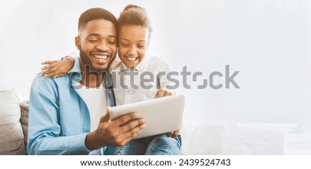 Little girl watching cartoon on tablet with father, spending time together at home