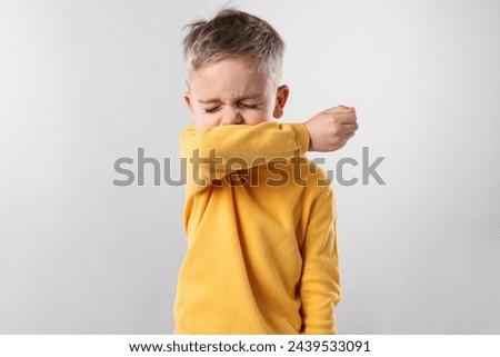 Sick boy coughing on gray background. Cold symptoms Royalty-Free Stock Photo #2439533091