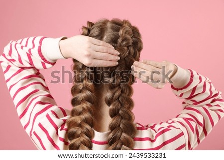 Woman with braided hair on pink background, back view