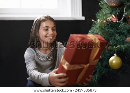 Girl, child and gift by Christmas tree in home, festive season and present for celebration on xmas. Female person, kid and happy for package on religious holiday, living room and love for tradition