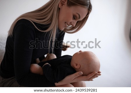 A beautiful girl in black golf holding  her two momth old baby