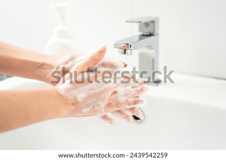 Woman hands are turning on the faucet at home and washing hands with clean water and soap for good hygiene. Royalty-Free Stock Photo #2439542259