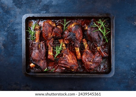 Traditional braised slow cooked lamb knuckle in red wine sauce with herbs served as top view in a backing form  Royalty-Free Stock Photo #2439545361
