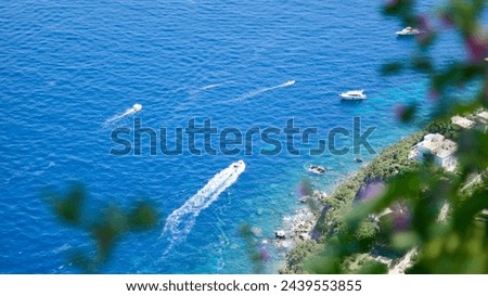 This picture was taken during a vacation to Capri, Italy from the Ana Capri, which is the top part of the Capri. Also, this picture contains a wonderful seaside view with boats and pieces of land.