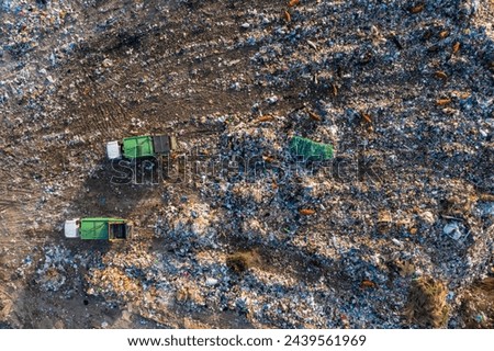 Aerial top down view of garbage trucks unload pile of waste at landfill. Dump of unsorted waste garbage pile in trash dump. Environmental pollution and ecological disaster. View from drone Royalty-Free Stock Photo #2439561969