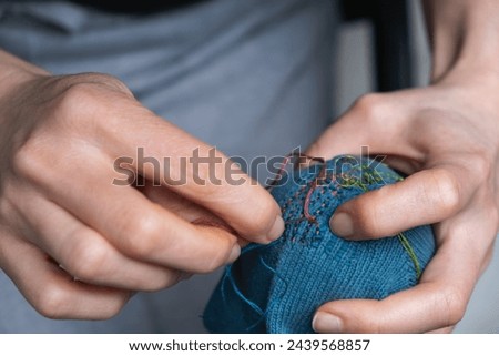 Mending clothes. Visible mending repairing sock. Darning old socks, reducing waste, slow fashion. Repair concept, selective focus. Royalty-Free Stock Photo #2439568857