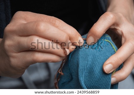 Mending clothes. Visible mending repairing sock. Darning old socks, reducing waste, slow fashion. Repair concept, selective focus. Royalty-Free Stock Photo #2439568859