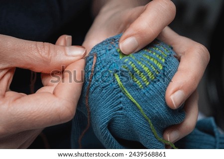 Mending clothes. Visible mending repairing sock. Darning old socks, reducing waste, slow fashion. Repair concept, selective focus. Royalty-Free Stock Photo #2439568861