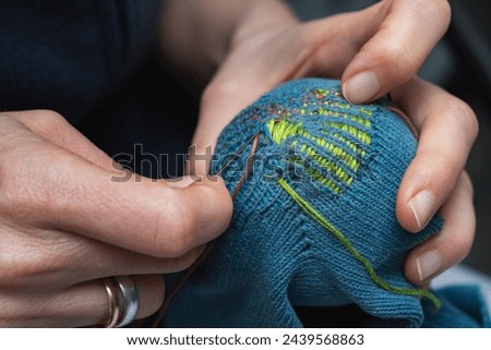 Mending clothes. Visible mending repairing sock. Darning old socks, reducing waste, slow fashion. Repair concept, selective focus. Royalty-Free Stock Photo #2439568863