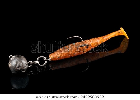 Orange fishing lure, plastic shad fish, with double hook and lead sinker, isolated on black background Royalty-Free Stock Photo #2439583939
