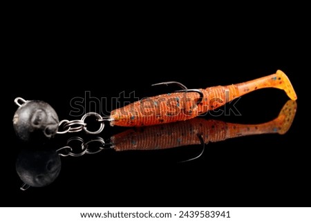Orange fishing lure, plastic shad fish, with double hook and lead sinker, isolated on black background Royalty-Free Stock Photo #2439583941