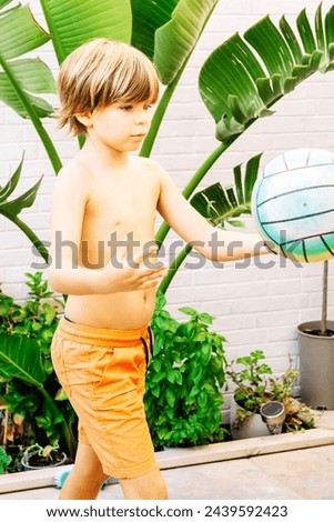 Caucasian blond boy, 9 years old, playing soccer, throwing a ball floating in front of his eyes, outdoors. Vertical.