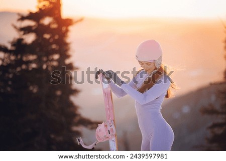 Happy young woman snowboarder in retro style of sportswear and pink thermal underwear on background of snow resort Sheregesh, sunset.