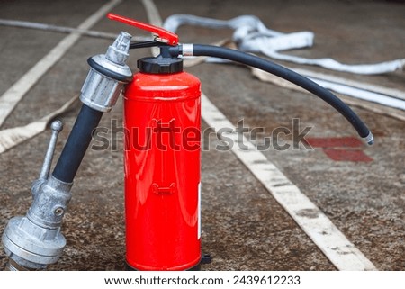 Red fire extinguisher cylinder with unwound fire hoses. Royalty-Free Stock Photo #2439612233