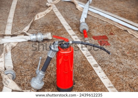 Red fire extinguisher cylinder with unwound fire hoses. Royalty-Free Stock Photo #2439612235