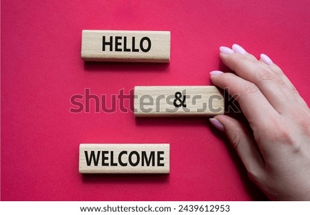 Hello and Welcome symbol. Concept words Hello and Welcome on wooden blocks. Beautiful red background. Businessman hand. Business and Hello and Welcome concept. Copy space.