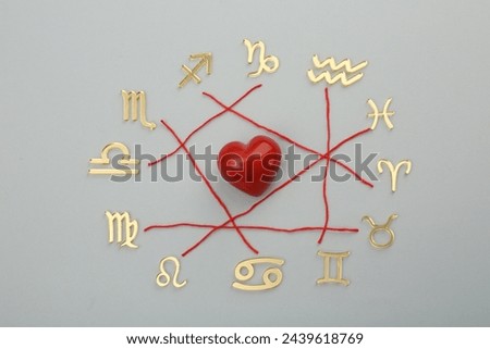 Zodiac compatibility. Signs, red heart and threads on grey background, flat lay Royalty-Free Stock Photo #2439618769