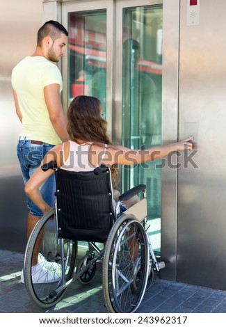 Young husband and wife on wheelchair getting out from passenger lift