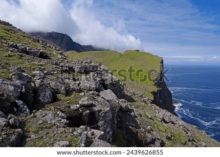 Rocky slopes transition to sheer cliffs at sea's edge along the remote, uninhabited north coast of Vagar, Faroe Islands