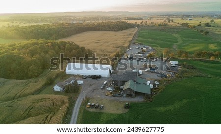 A high-up aerial drone shot of a farmhouse, farm fields and Barns at sunset