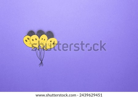 Four yellow handmade smiling balloons isolated on purple background. Concept of the happiest day of the year, yellow day. Image with copy space.