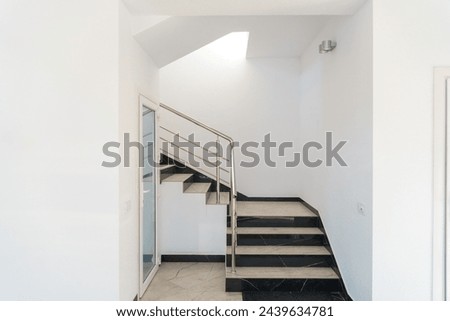 A wide staircase along the large windows in an office building. Modern interior of the lobby of an office building with large spacious windows. Illuminated long corridor in a modern business center Royalty-Free Stock Photo #2439634781