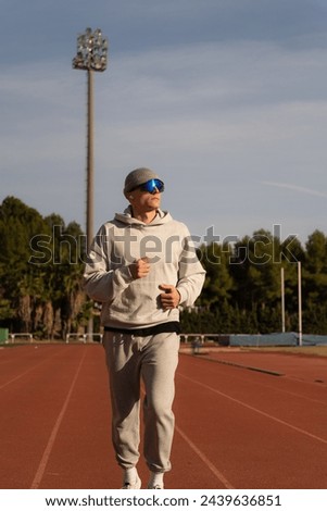 Early morning runner training on the athletics track. Vertical photo. Looking towards the sun. Copy space background