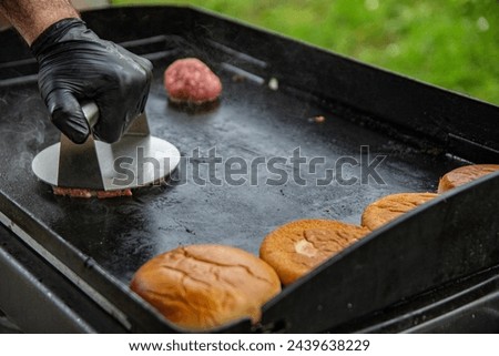 a hand with a round smasher smashing a burger Royalty-Free Stock Photo #2439638229