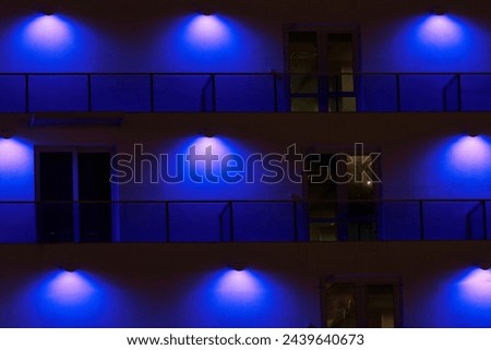  Architectural illumination of building fosad with LED lights. A fragment of a multi-story building in blue light. Night shooting at long shutter speed.                              