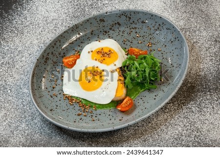 Sunny-side-up eggs with tomatoes and green-stuff Royalty-Free Stock Photo #2439641347