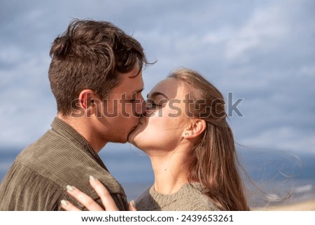 Young couple kissing on a beach, under a cloudy sky. Perfect for stories on romance and youthful love. High quality photo