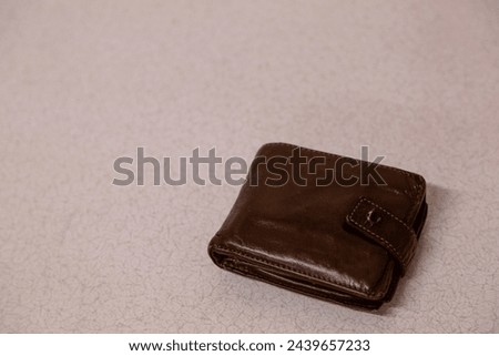 Brown leather wallet, Image shows a aged and well used mens wallet showing signs of wear and tear with a light background