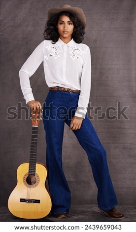 Woman, fashion and musician cowgirl in studio, western clothing and guitar with confidence. Native American, female person in serious portrait for trendy countryside culture, isolated on background