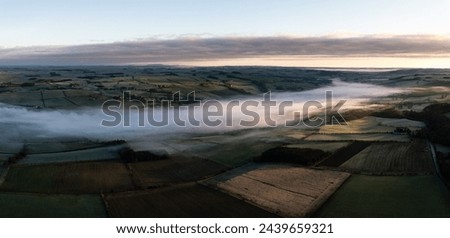 Aerial view of low lying mist or cloud inversion along the River Tyne valley at Haydon Bridge near Hexham on a cold Winter morning Royalty-Free Stock Photo #2439659321
