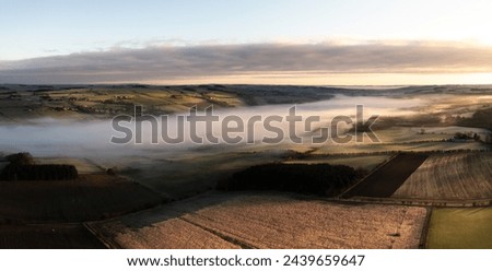 Aerial view of low lying mist or cloud inversion along the River Tyne valley at Haydon Bridge near Hexham on a cold Winter morning Royalty-Free Stock Photo #2439659647