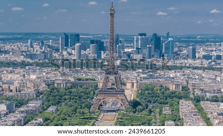 Aerial view from Montparnasse tower with Eiffel tower with people on a viewpoint and La Defense district on background timelapse in Paris, France. Top view from observation deck at sunny summer day.
