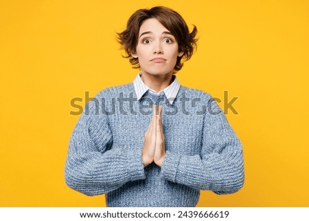 Young woman she wearing grey knitted sweater shirt casual clothes hold hands folded in prayer gesture, begging about something isolated on plain yellow background studio portrait. Lifestyle concept Royalty-Free Stock Photo #2439666619