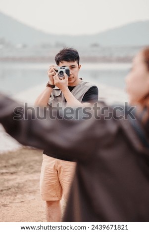 Male photographer composes a shot with his vintage camera, capturing his subject in a natural lakeside setting.