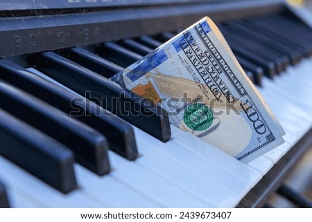 A keyboard with a $100 bill on it. Concept of playfulness and whimsy, as it is not a typical scene to see a large amount of money on a keyboard
