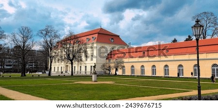 Image of Charlottenburg Palace in Berlin. The photo shows the main facade of the palace, which is decorated with statues, columns, and elaborate carvings. The palace is surrounded by a large garden
