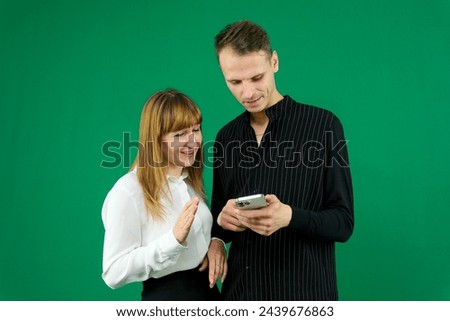 man and woman with gadgets tablet phone in hands on green background talking laugh holding meeting learning to work on Internet flirting relationships flirting couple solving issue positive emotions